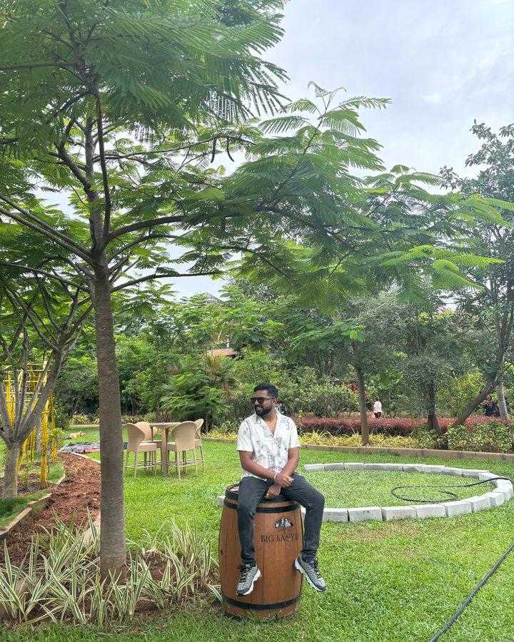 Abhishek sitting on a barrel in a green garden